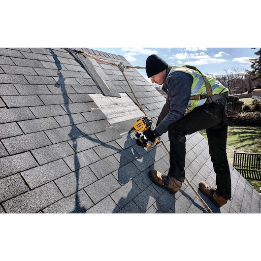 Cordless Coil Roofing Nailer being used by a construction worker on the roof to fix a roofing panel